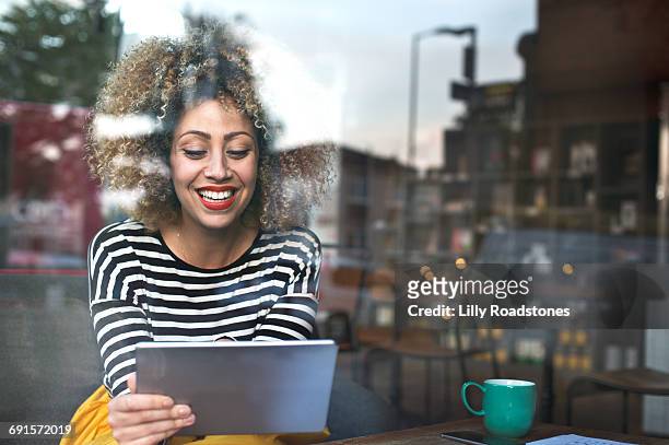 woman using tablet computer in coffee shop - leanincollection stock pictures, royalty-free photos & images