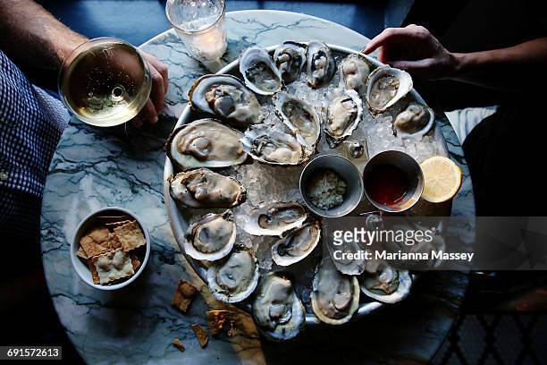 a couple enjoying raw oysters - fische und meeresfrüchte stock-fotos und bilder