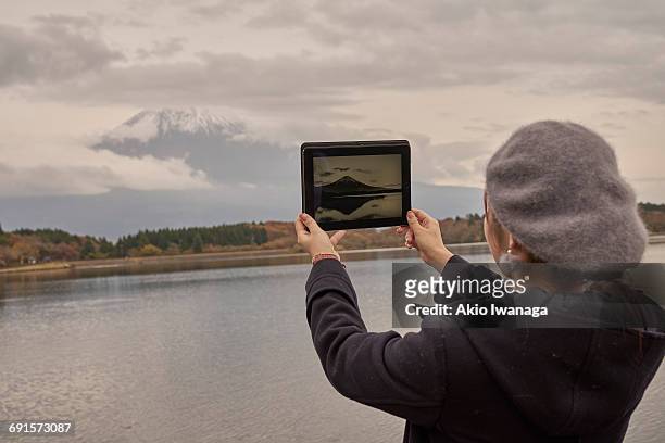 a woman looking at mt. fuji on a tablet - akio iwanaga 個照片及圖片檔