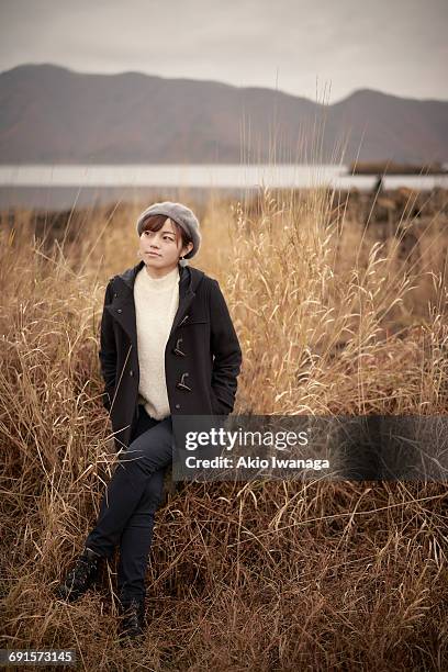 a woman sitting in the autumn grassland - akio iwanaga stock pictures, royalty-free photos & images