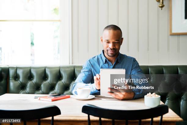 man at table with tablet - autonomo smartphone tablet fotografías e imágenes de stock