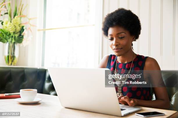 woman using laptop at table - camisa sin mangas fotografías e imágenes de stock
