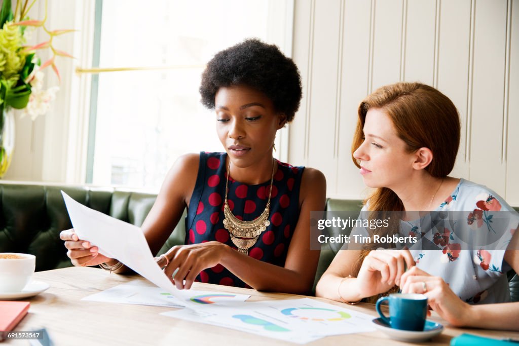 Two women with infographics at table.