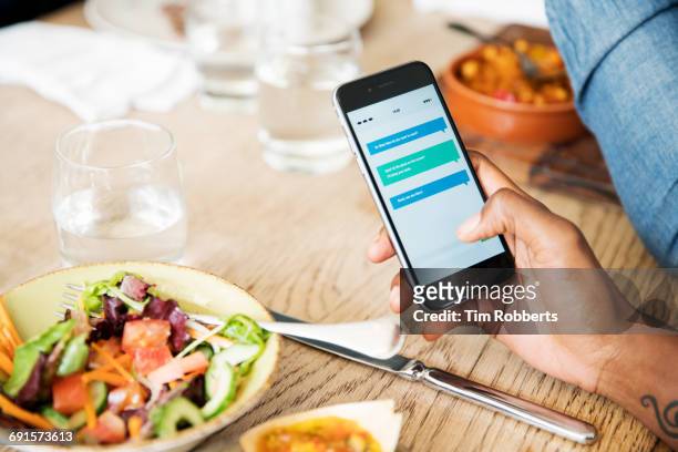 close up of smart phone at lunch - african american restaurant texting stockfoto's en -beelden