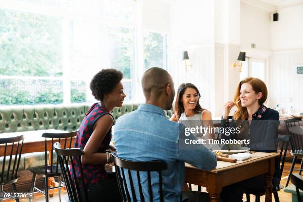 four people having lunch, one eating french fries. - group of people cafe stockfoto's en -beelden