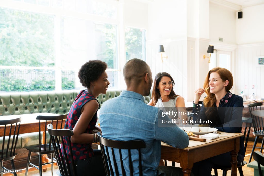 Four people having lunch, one eating french fries.