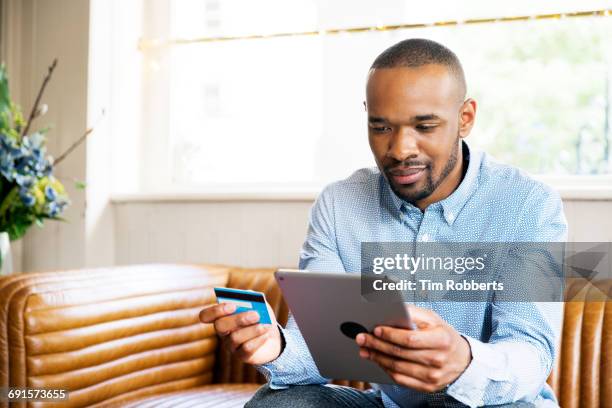 man with tablet and credit card - man reading card stock pictures, royalty-free photos & images