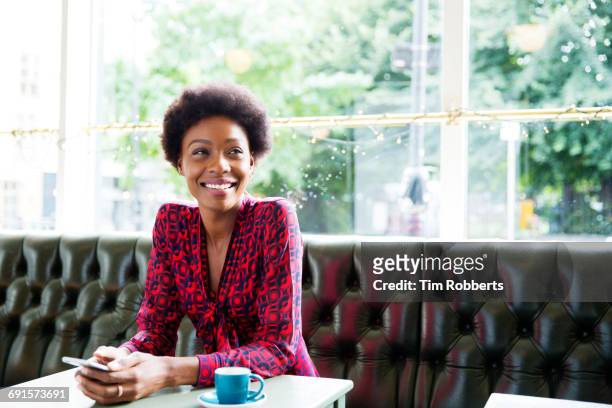 woman smiling with smartphone, at table - red saucer stock pictures, royalty-free photos & images