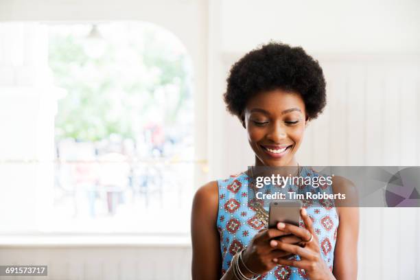 woman smiling using smart phone - cafehaus stock-fotos und bilder