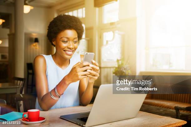 woman using smartphone in cafe - mobile device on table stock-fotos und bilder