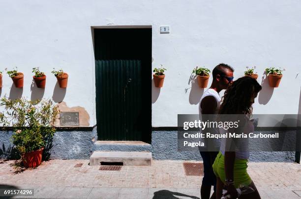 Young couple walking down a narrow street passing by typical white house doorway.