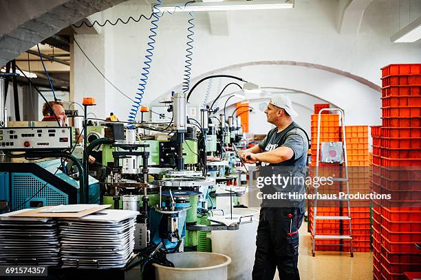 industrial working standing between machines - industriearbeider stockfoto's en -beelden
