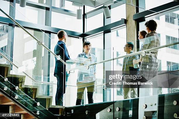businesswoman leading meeting on office stairs - glass stair railing fotografías e imágenes de stock