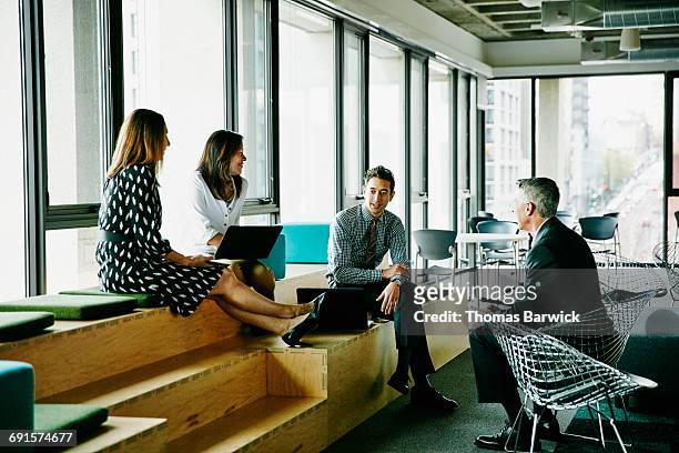 colleagues having informal meeting in office - wisdom knowledge modern stockfoto's en -beelden