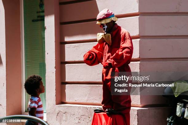 Little boy looking at mimo artist performing like a clown on a street.