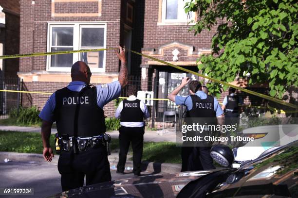 Chicago police officer glances out the window of his vehicle at the scene of a shooting near 59th and South Peoria streets in the Englewood...