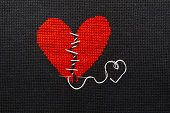 Two halves heart embroidered red thread on black fabric. Two halves heart sewn with black thread.