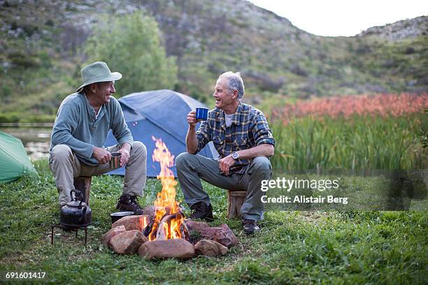 senior men camping outdoors - camp fire - fotografias e filmes do acervo