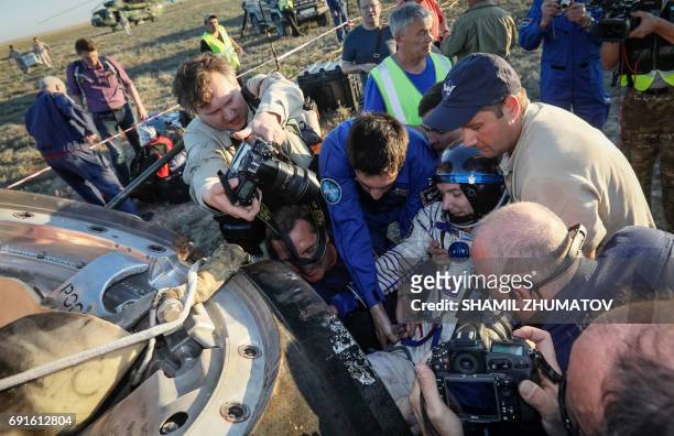 Ground personnel help French astronaut Thomas Pesquet to get out of the Soyuz MS-03 space capsule after landing in a remote area outside the town of...