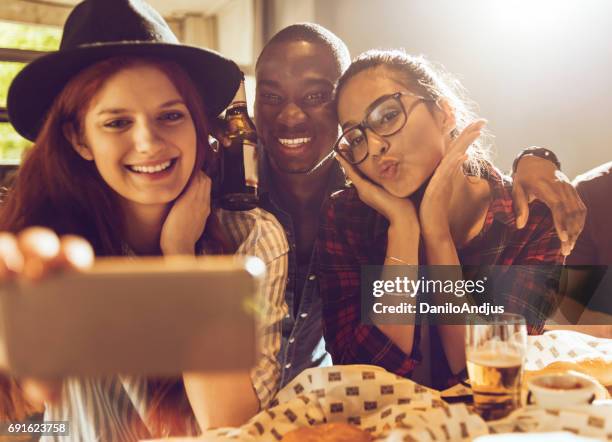 vrolijke groep vrienden nemen van een selfie - sun flare on glass stockfoto's en -beelden