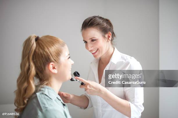 dermatologist inspecting patient face skin with dermatoscope - dermatologists talking to each other patient stock pictures, royalty-free photos & images