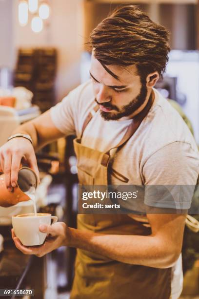 young barista pouring latte art - latte art stock pictures, royalty-free photos & images