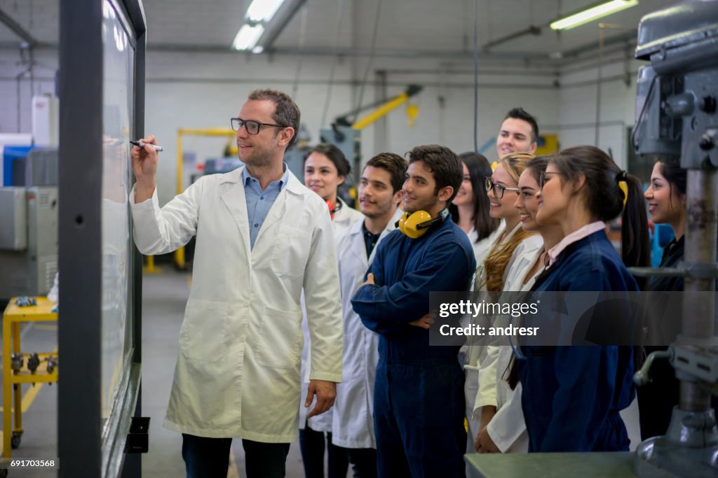 Engineering students with their teacher writing on the board