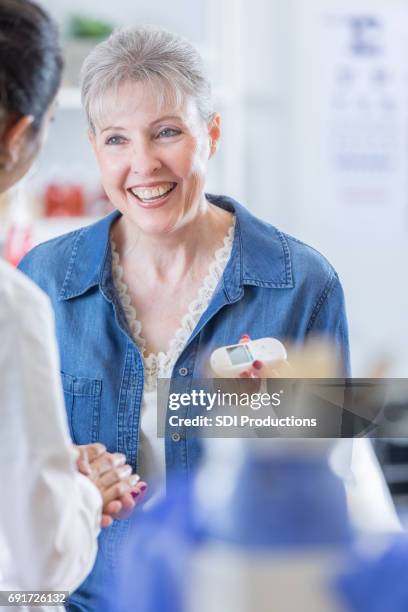 healthcare professional checks senior woman's blood sugar - dendochronology stock pictures, royalty-free photos & images