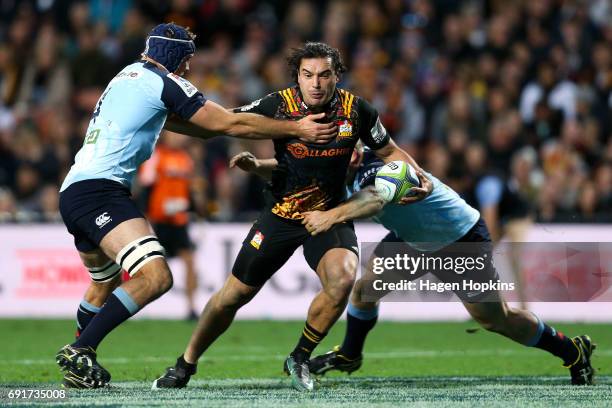 James Lowe of the Chiefs offloads in the tackle of Tom Robertson and Dean Mumm of the Waratahs during the round 15 Super Rugby match between the...