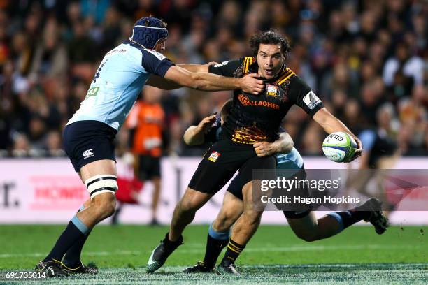 James Lowe of the Chiefs offloads in the tackle of Tom Robertson and Dean Mumm of the Waratahs during the round 15 Super Rugby match between the...