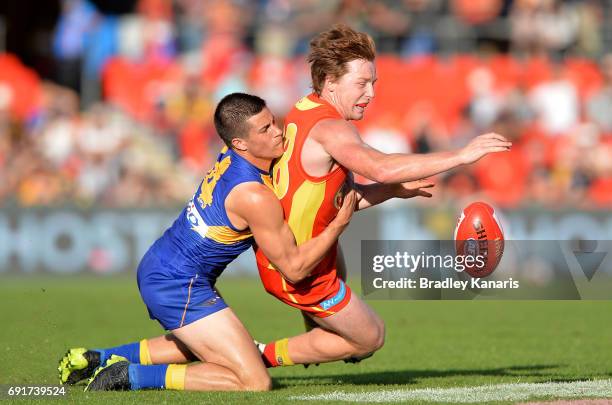 Suns player Jesse Joyce is pressured by the defence of West Coast Eagles player Liam Duggan during the round 11 AFL match between the Gold Coast Suns...