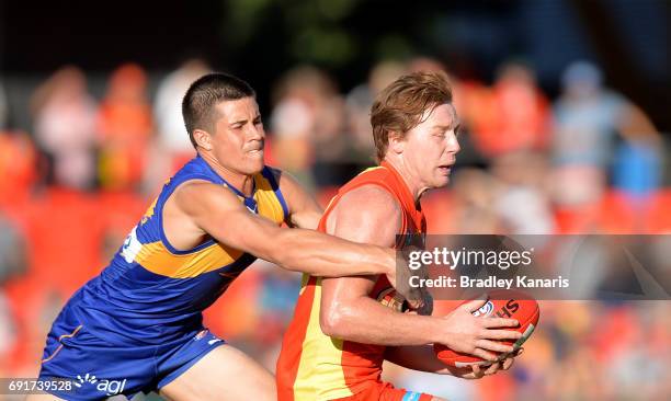 Suns player Jesse Joyce is pressured by the defence of West Coast Eagles player Liam Duggan during the round 11 AFL match between the Gold Coast Suns...