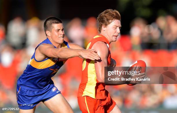 Suns player Jesse Joyce is pressured by the defence of West Coast Eagles player Liam Duggan during the round 11 AFL match between the Gold Coast Suns...