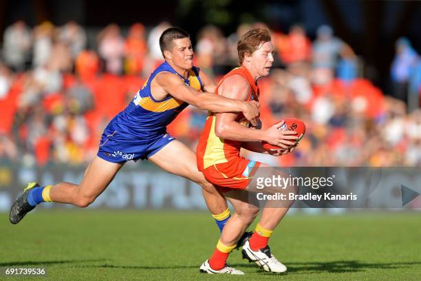 Suns player Jesse Joyce is pressured by the defence of West Coast Eagles player Liam Duggan during the round 11 AFL match between the Gold Coast Suns...