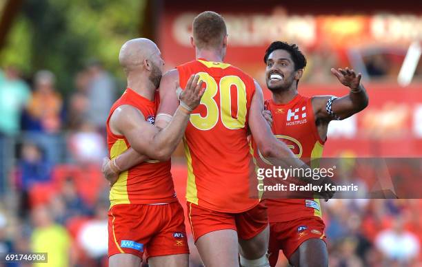 Suns player Peter Wright is congratulated by team mates after kicking the winning goal during the round 11 AFL match between the Gold Coast Suns and...