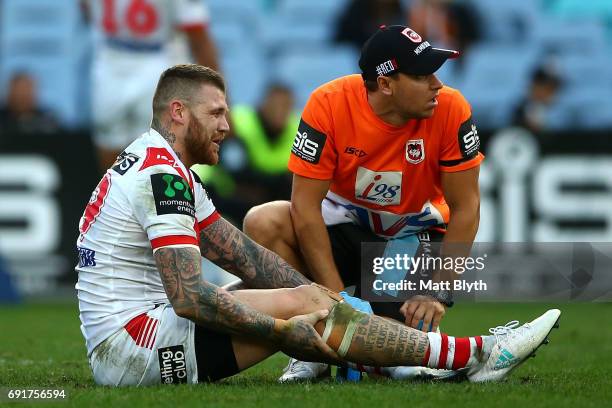 Josh Dugan of the Dragons seeks treatment from a trainer after an injury during the round 13 NRL match between the St George Illawarra Dragons and...