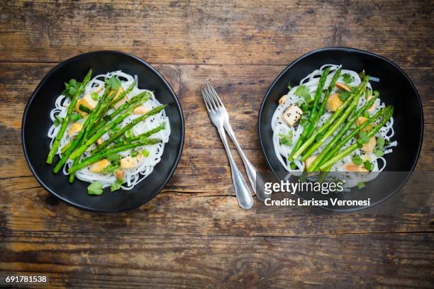 two bowls of vegan pad thai with mini green asparagus and tofu - larissa veronesi bildbanksfoton och bilder