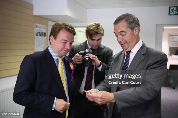 Former UKIP leader Nigel Farage looks at a label for an ale pump with Tim Aker, UKIP candidate for Thurrock, as they campaign ahead of the general...
