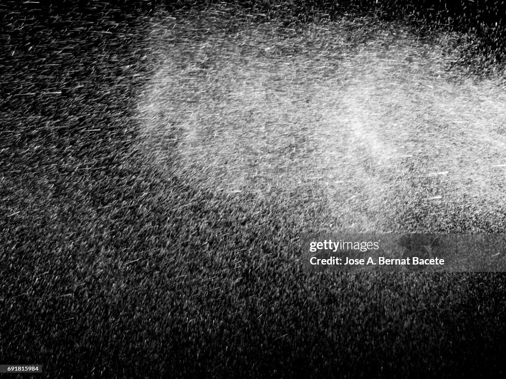 Pattern of pressured water droplets floating in the air on a black background