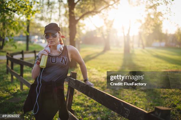 ein mädchen trinken limonade beim ausruhen nach dem joggen - mp3 juices stock-fotos und bilder