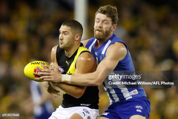 Shaun Grigg of the Tigers is tackled by Lachlan Hansen of the Kangaroos during the 2017 AFL round 11 match between the North Melbourne Kangaroos and...