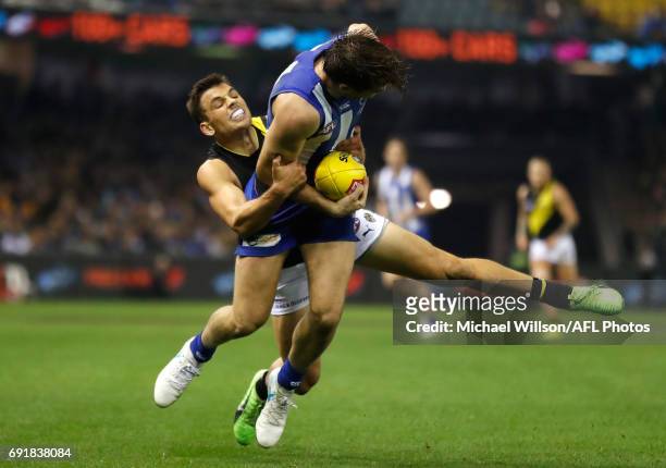 Luke McDonald of the Kangaroos is tackled by Sam Lloyd of the Tigers during the 2017 AFL round 11 match between the North Melbourne Kangaroos and the...