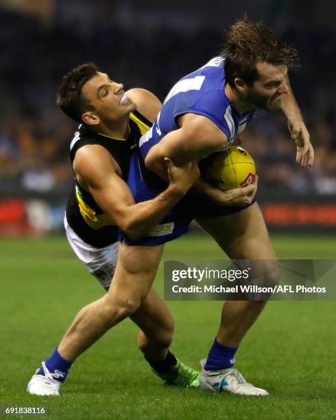 Luke McDonald of the Kangaroos is tackled by Sam Lloyd of the Tigers during the 2017 AFL round 11 match between the North Melbourne Kangaroos and the...