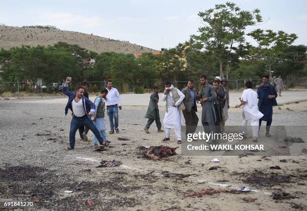 Graphic content / TOPSHOT - An angry Afghan man throws a rock at what was thought to be the remains of one of the attackers at the site of a series...