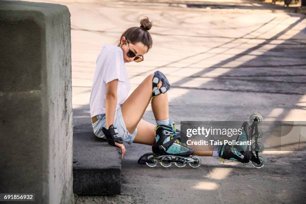 woman sitting on the floor wearing inline skates in an industrial area - germany, bavaria, wertheim - inline skating fotografías e imágenes de stock