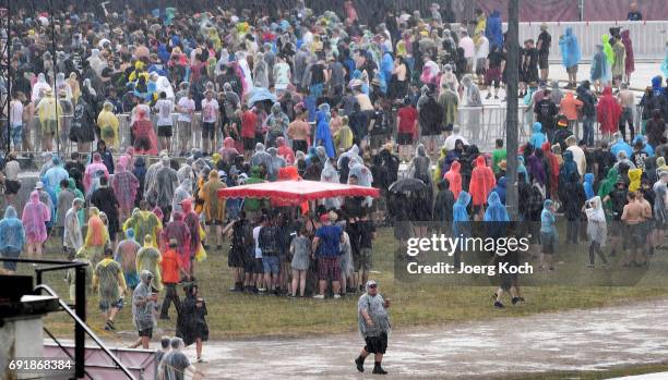 Visitors try to cover from heavy rain during the 'Rock Im Park' music festival at Zeppelinfeld on June 3, 2017 in Nuremberg, Germany.