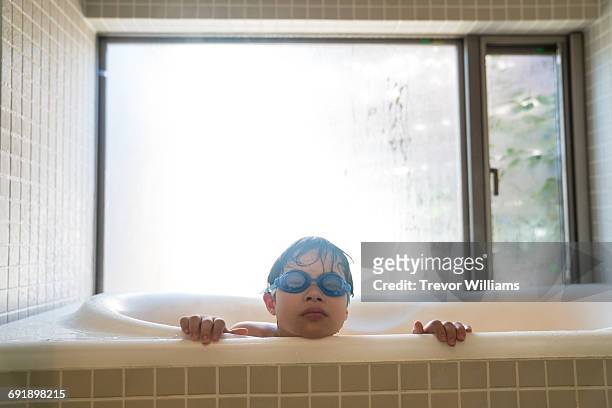 Special needs boy peeking out of the bath tub