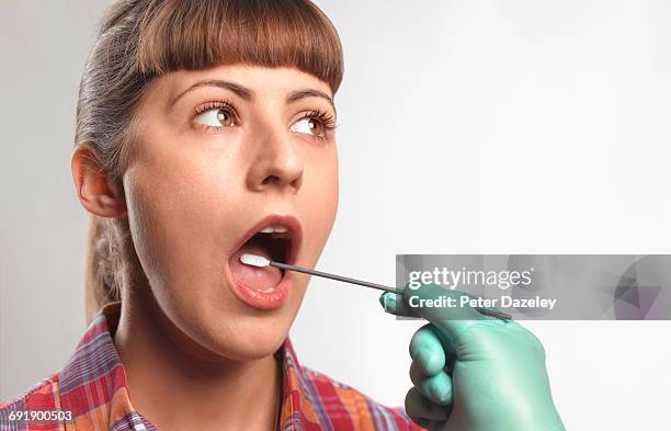 person putting dna test swab into woman's mouth - saliva stock pictures, royalty-free photos & images