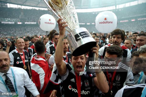 Besiktas' Brazilian defender Adriano holds the trophy as players celebrate their 2016-2017 Turkish league champion title after the Turkish Spor Toto...