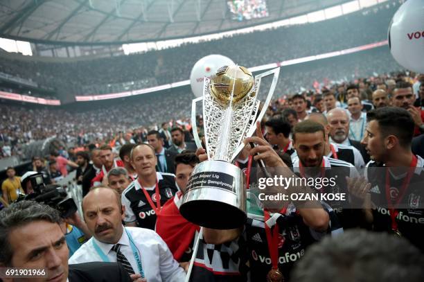 Besiktas' Brazilian defender Adriano holds the trophy as he and teammates celebrate their 2016-2017 Turkish league champion title after the Turkish...